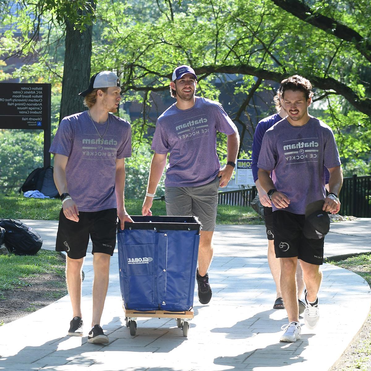 四名身穿紫色波胆网站男子曲棍球t恤的年轻人推着一辆移动的手推车