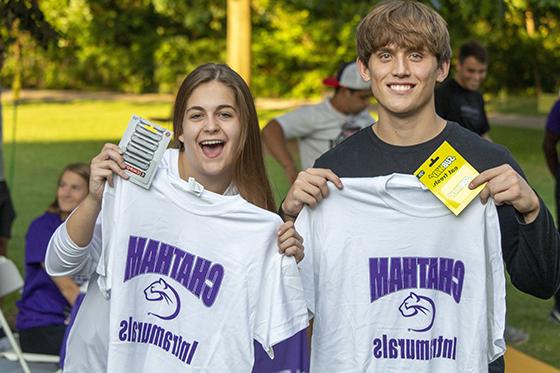 图为两名波胆网站的学生举着他们的校内运动t恤，面带微笑